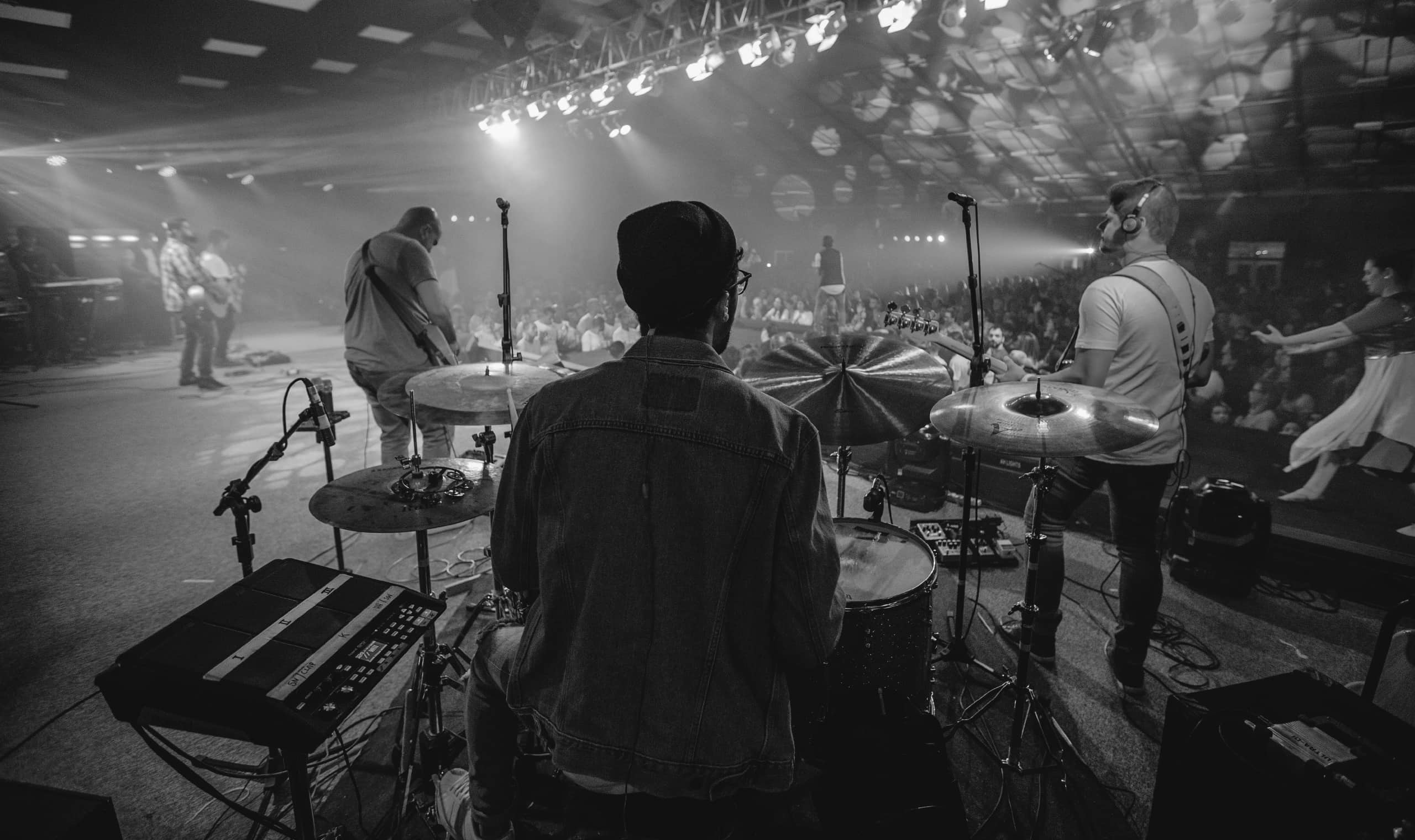 View behind drummer of a band at a live show